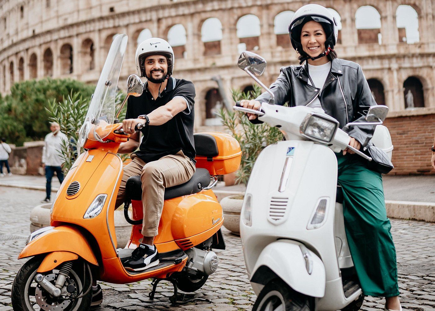Touristes conduisant une Vespa devant le Colisée à Rome